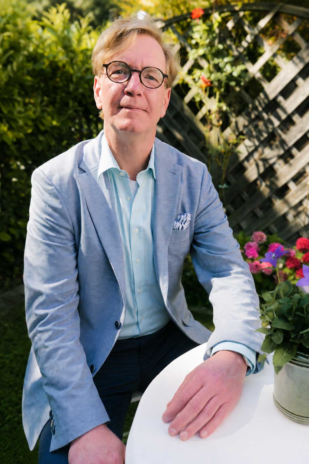 Martin Fryburg, freier Hochzeitsredner aus Paderborn, sitzt in einem Garten an einem weißen Tisch